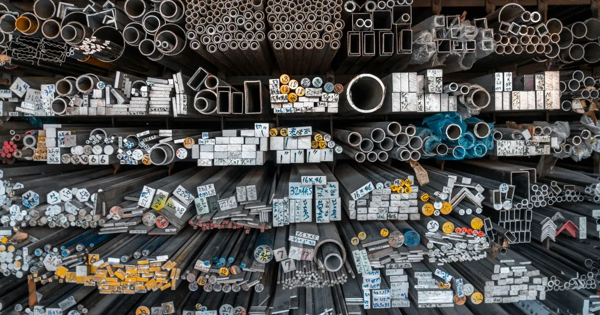 Steel bar and tube stock stored on racks in a metal supplier warehouse, the raw material for 4140 steel machining and other carbon steel parts